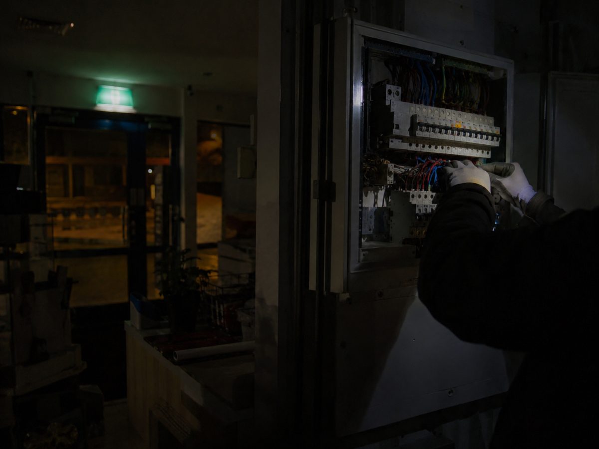 Electrician working on a commercial switchboard at night